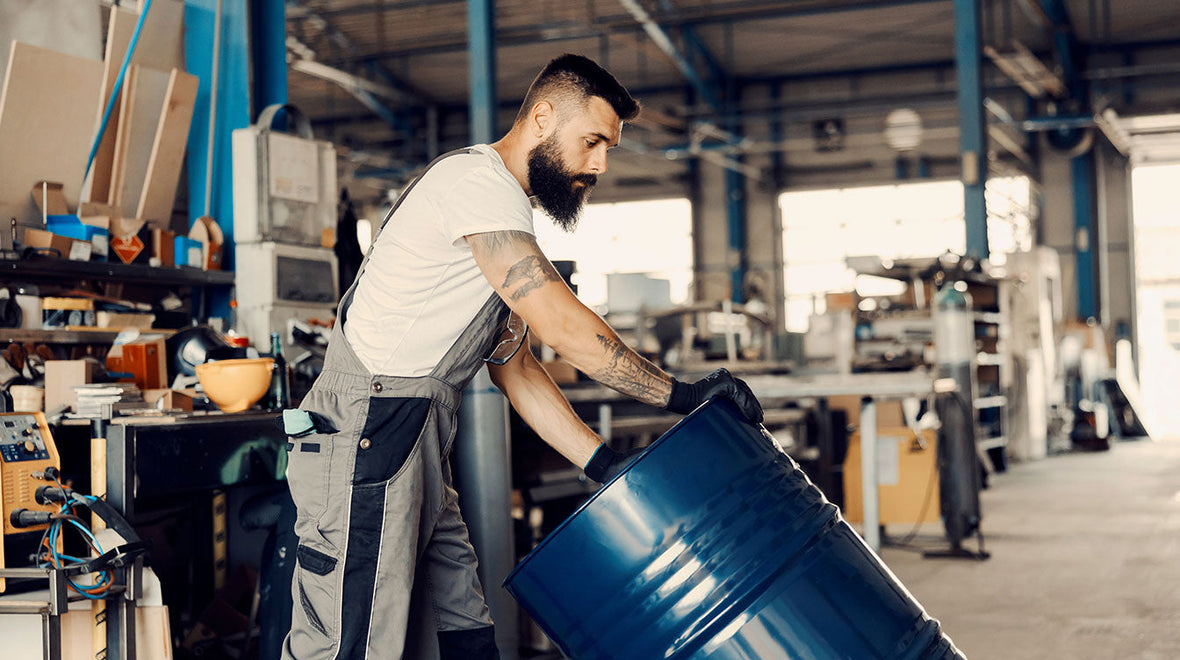 Man rolling a barrel of Hydraulic Jack Oil
